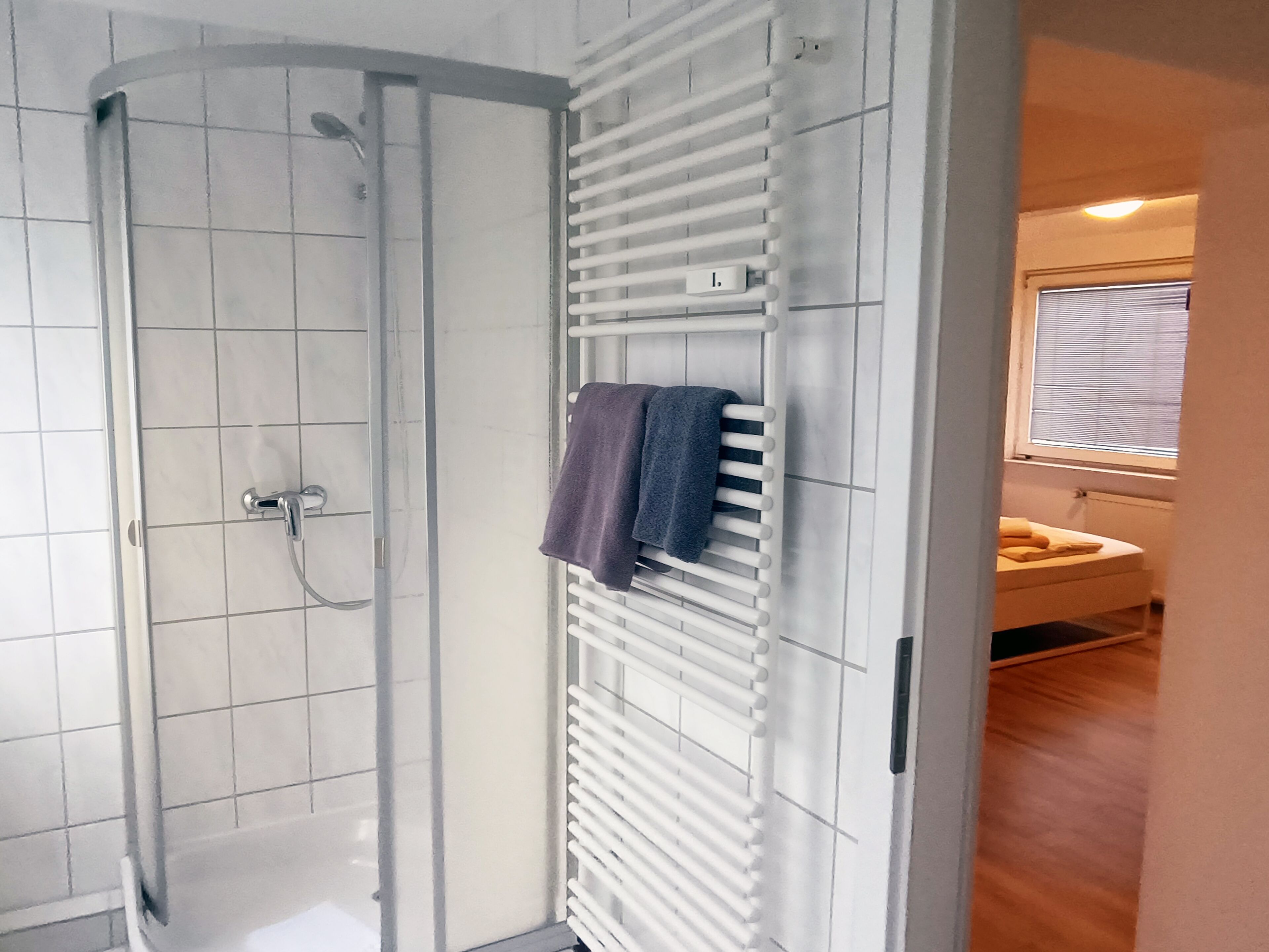 A bathroom with a shower, a towel rack, and a toilet.