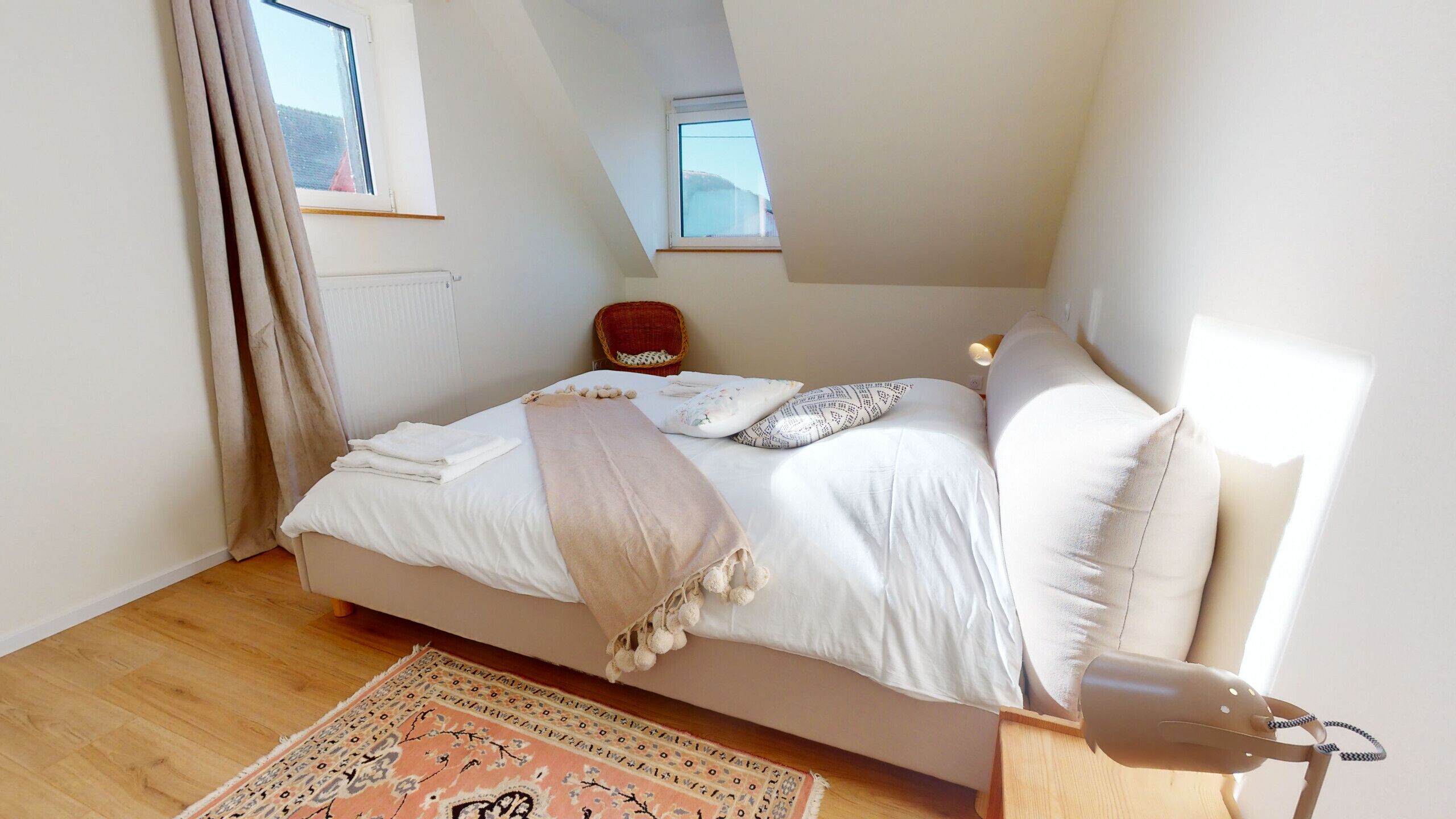 A bedroom with a bed, a chair, a window, and a rug.
