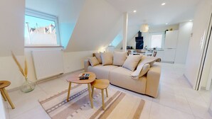 Een moderne woonkamer met een bank, een klein rond tafeltje en een raam met uitzicht op een woonwijk.