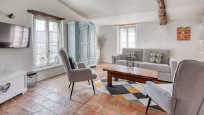Un salon comprenant un canapé, des fauteuils, une table basse, un téléviseur et une cheminée.