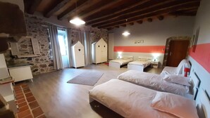 A hotel room with two beds, a stone wall, a wooden ceiling, and a red accent wall.