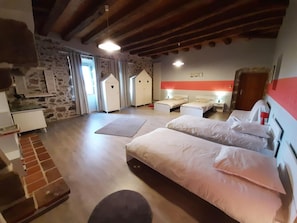 A hotel room with two beds, a stone wall, a wooden ceiling, and a red accent wall.