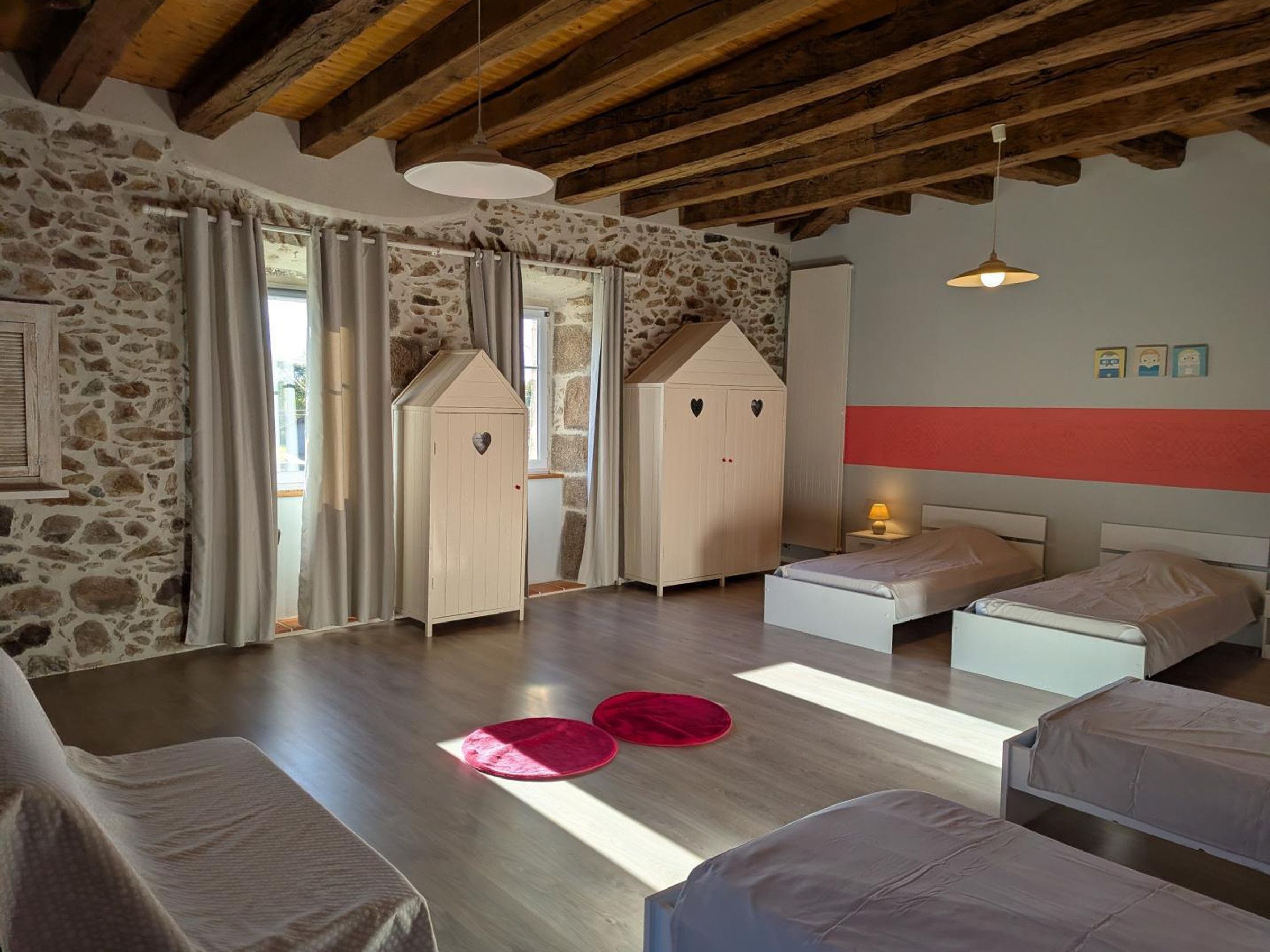 Ein Schlafzimmer mit Steinwand, Holzbalken, einem Bett, einem Nachttisch und einem Kleiderschrank.
