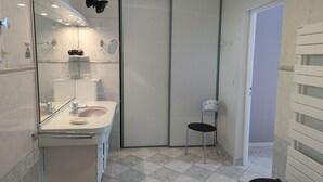 A modern bathroom with a glass shower enclosure, a white sink, and a black chair.