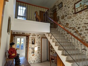 A staircase with stone walls and a wooden handrail leading to a second floor.