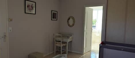 Un dormitorio con una cama, un escritorio, una silla, un armario y una puerta que da a un balcón.