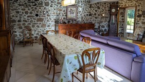 A dining area with a stone wall, wooden furniture, and a table with a leaf-patterned tablecloth.