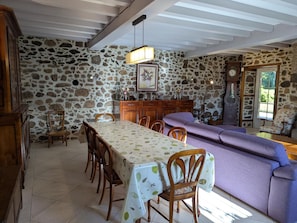 A dining area with a stone wall, wooden furniture, and a table with a leaf-patterned tablecloth.