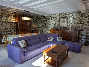 A living room with a purple sofa, wooden cabinets, and a stone wall.