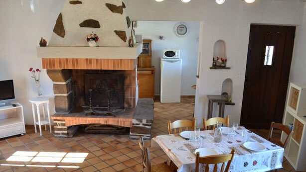 A dining area with a fireplace, a television, and a tiled floor.