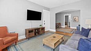 Ein Wohnzimmer mit Flachbildfernseher, Couch, Holztisch und TV-Schrank.