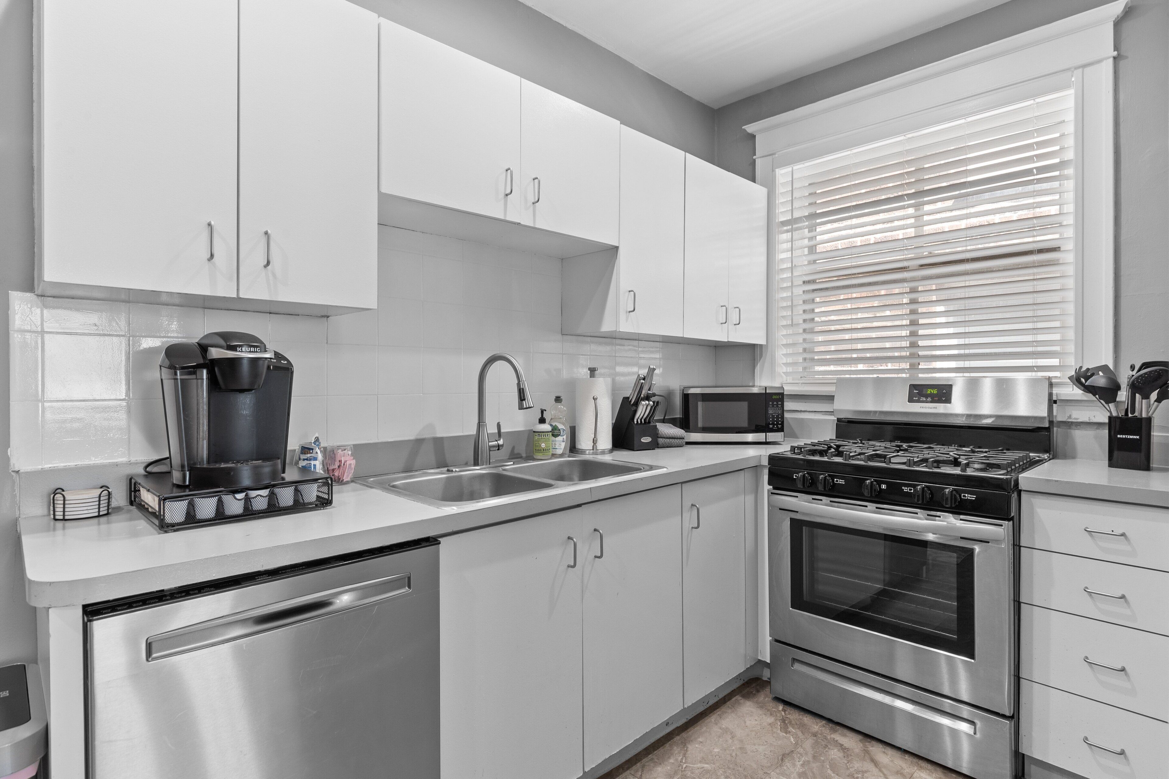 Una cocina moderna con electrodomésticos de acero inoxidable, armarios blancos y lavavajillas.