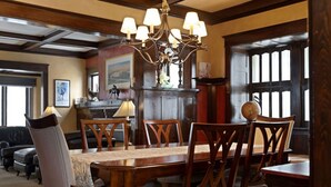 A dining area with a wooden table and chairs, a chandelier, and a view of the kitchen in the background. - Historic Cozy Home Walkable to DT w/ Pool Table (Kalispell)