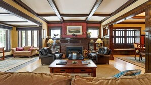 A spacious living room with a fireplace, leather sofas, and a coffee table. - Historic Cozy Home Walkable to DT w/ Pool Table (Kalispell)
