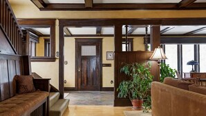 A spacious lobby with a wooden staircase, a large potted plant, and a sofa. - Historic Cozy Home Walkable to DT w/ Pool Table (Kalispell)