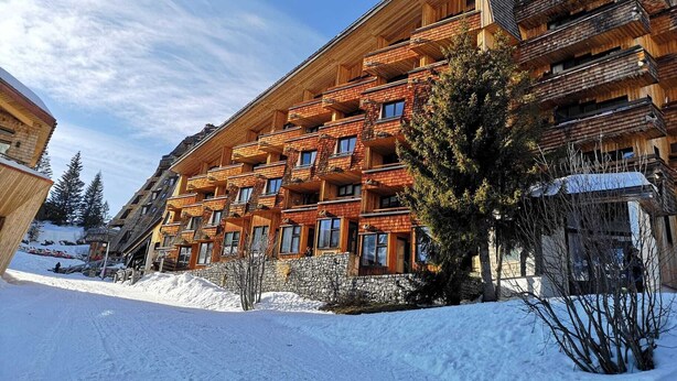 A multi-story wooden building with balconies, surrounded by snow.