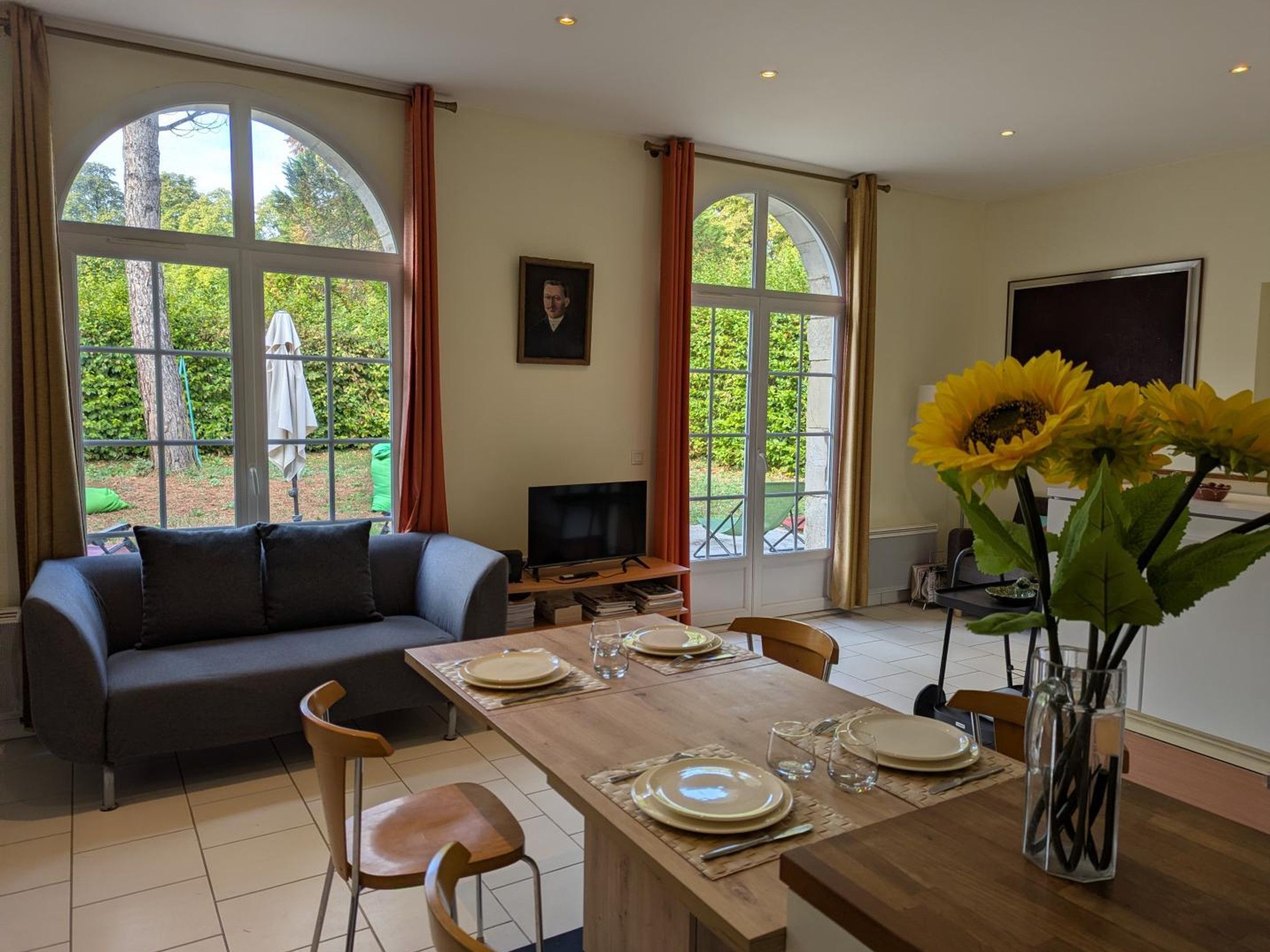 A dining area with a table set for four, a sofa, and a television in the background.