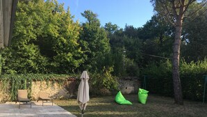 A patio with a stone floor, a covered table, and two green bean bags. - Charming Cottage with Private Gardens, Baby Gear, Near Cognac (Cognac)
