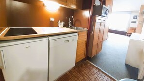 A compact kitchen with a Bosch dishwasher, a sink, wooden cabinets, and a microwave.