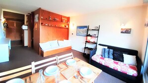 A compact living space with a dining area, a sofa, and a bookshelf.