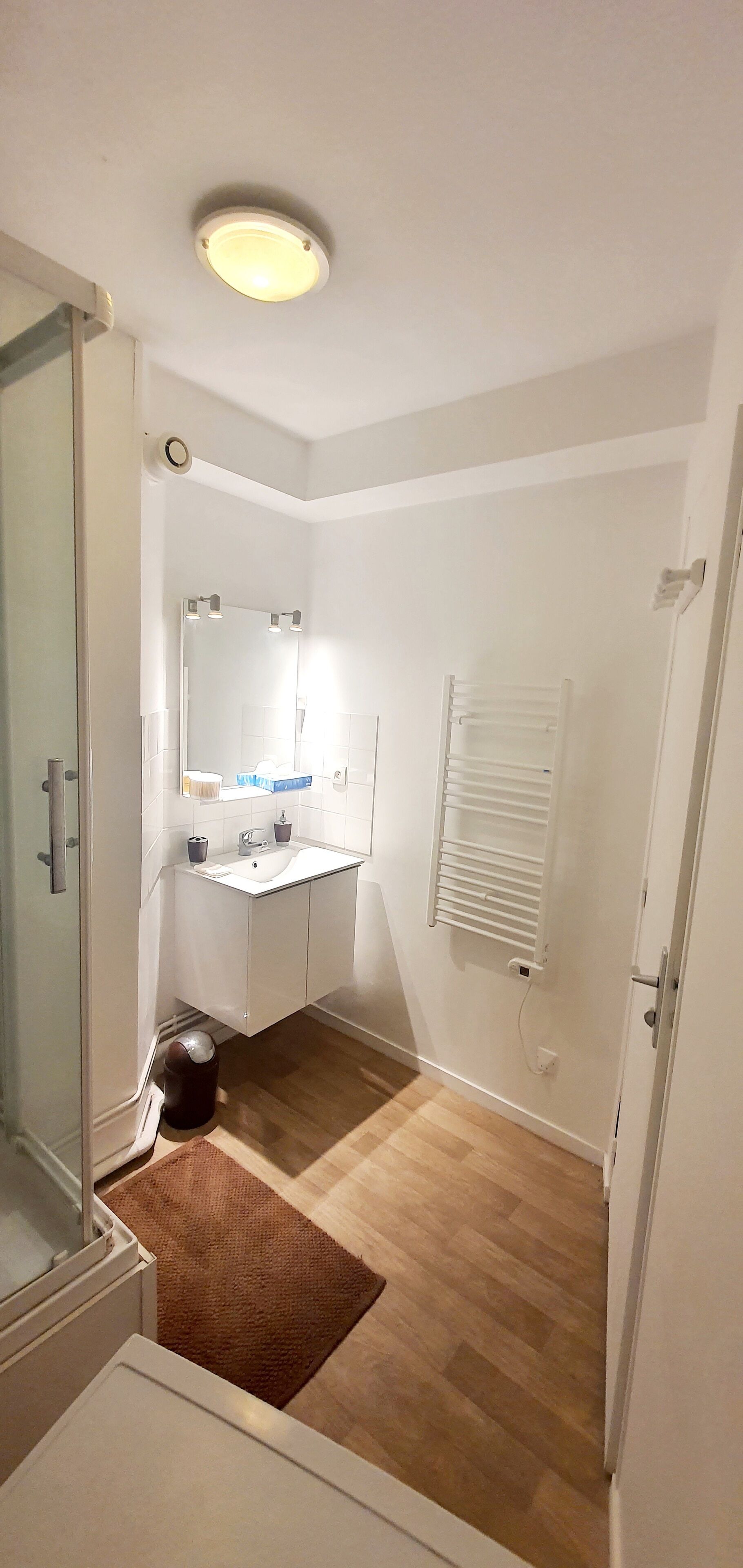 A small, clean bathroom with a shower, sink, and mirror.