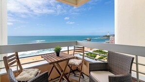 Un balcone con vista sull'oceano e su un faro, con mobili in vimini e un tavolino.