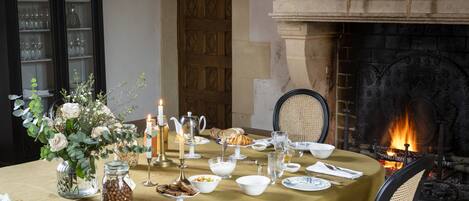 Una mesa de comedor dispuesta para una comida, con velas, chimenea y vista al fuego.