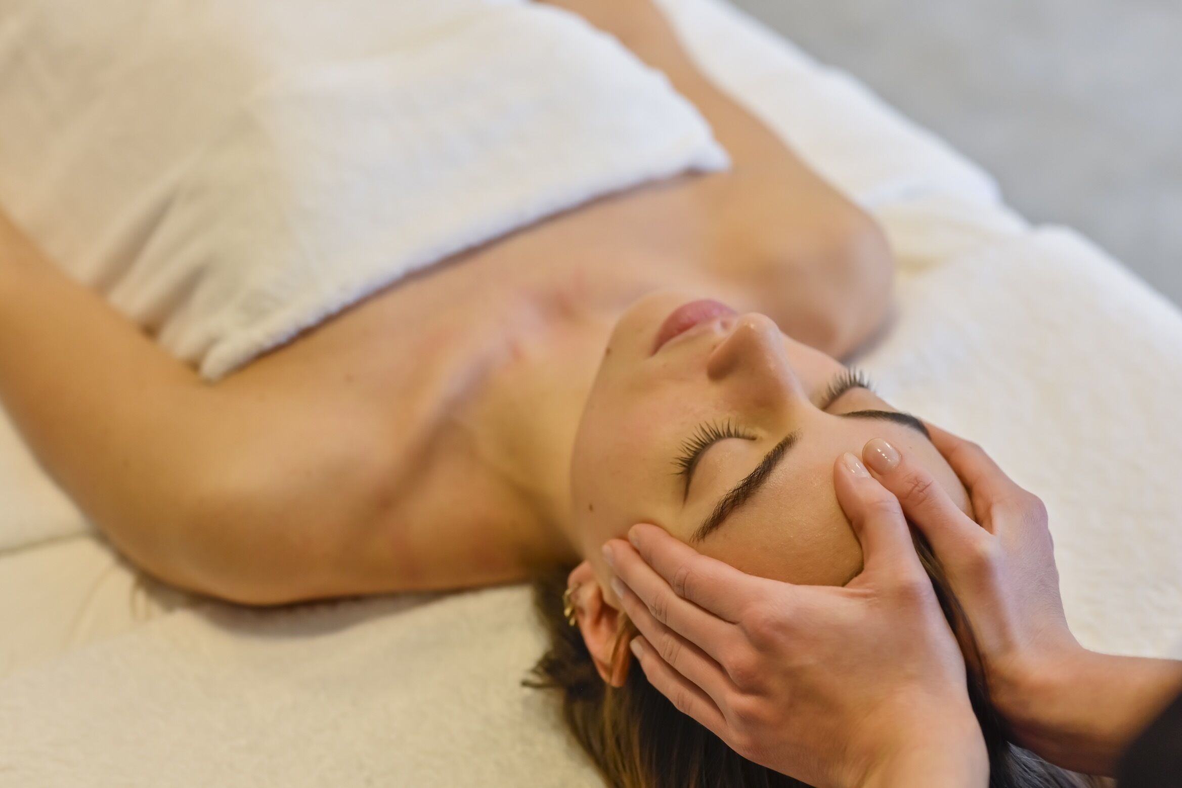 Une personne allongée sur une serviette blanche, en train de recevoir un soin du visage.