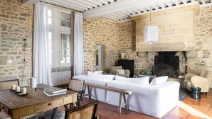 A rustic room with stone walls, a white sofa, a wooden table, and a fireplace. - Château Toulouse-Lautrec Malromé (Saint-André-du-Bois)