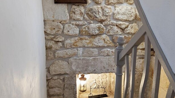 A staircase with a stone wall and a lantern on the landing.