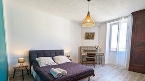 A bedroom with a bed, bedside tables, a desk, and a chair.