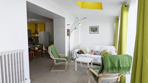A living room with a white sofa, two green armchairs, a white coffee table, and a floor lamp.