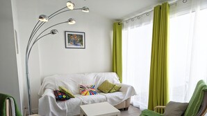 A modern living room with a white sofa, two green armchairs, a white coffee table, and a floor lamp.