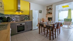 A modern kitchen with yellow cabinets, a built-in oven, and a dining area with wooden chairs and a table set for four.