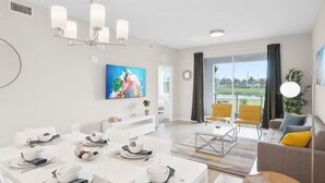 Una sala de estar moderna con comedor, televisor de pantalla plana y un ventanal con vistas.