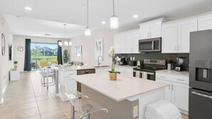 Una cocina moderna con armarios blancos, electrodomésticos de acero inoxidable y una isla grande.