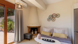 A cozy living room with a fireplace, a sofa with cushions, a coffee table, and a decorative wall piece.