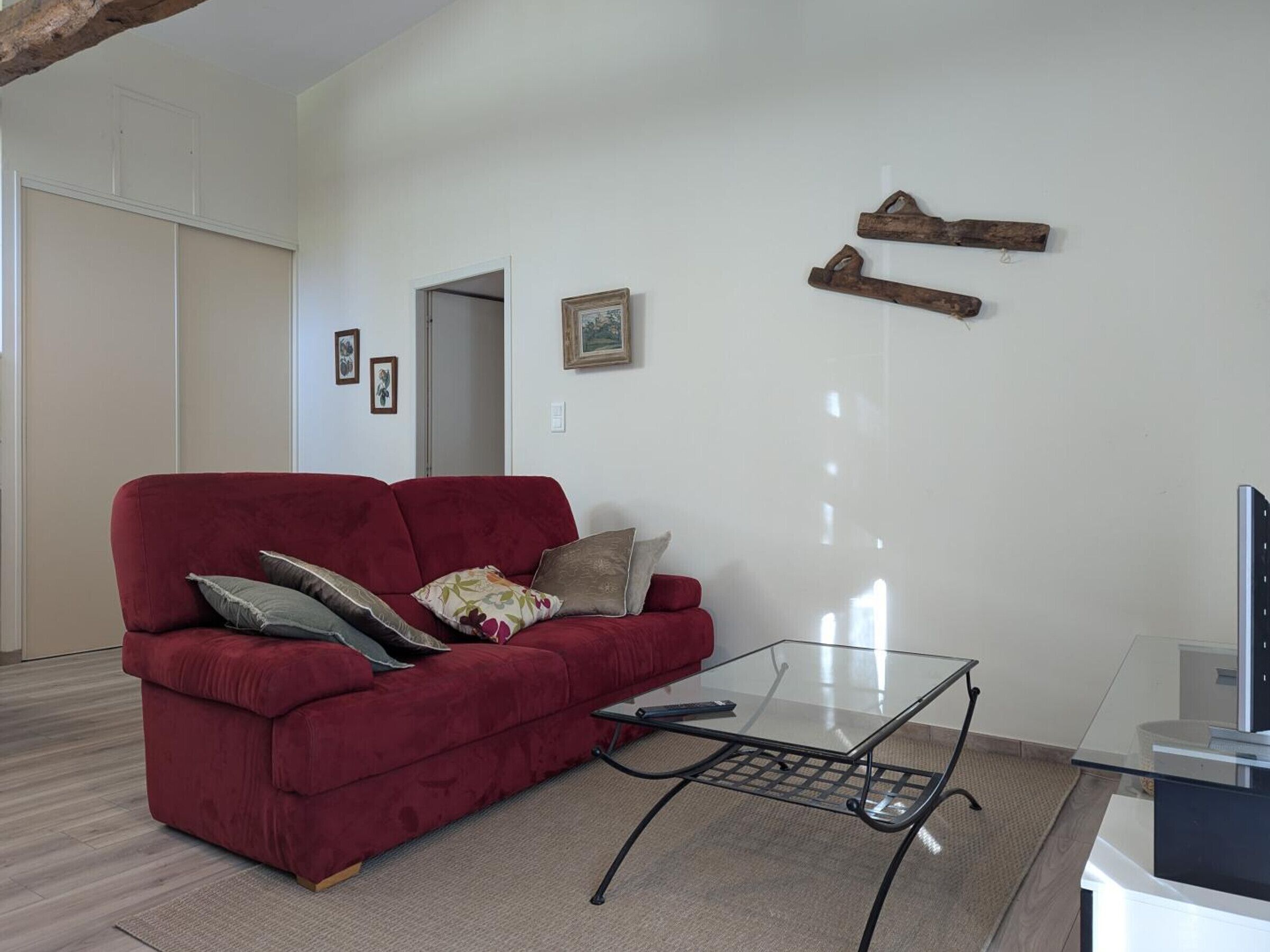 A living room with a red sofa, a glass coffee table, and a TV stand.