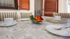 A dining table with a floral tablecloth, a glass bowl with flowers, and a cup and saucer. - Apartment Susa (Vir)