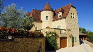 A stone building with a turret and a round tower, featuring a stone wall and a paved entrance. - Apartment with swimming pool and place of relaxation and leisure (Sarlat-la-Canéda)
