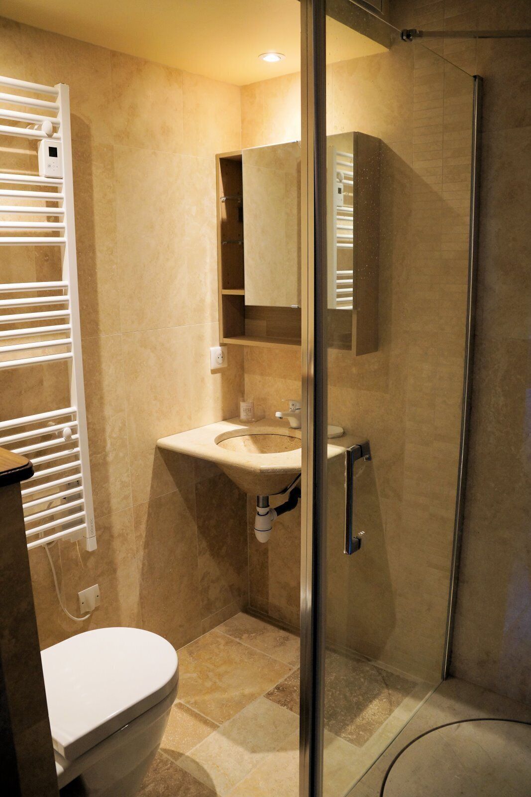 A bathroom with a toilet, sink, and glass-enclosed shower.