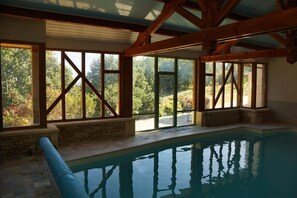 An indoor swimming pool with stone walls and large windows.