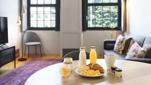 Uma mesa de café da manhã com croissants, ovos mexidos, uma garrafa de leite, um copo de suco de laranja e acompanhamentos.