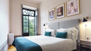 Quarto com uma cama grande, janela com vista e quadros nas paredes.