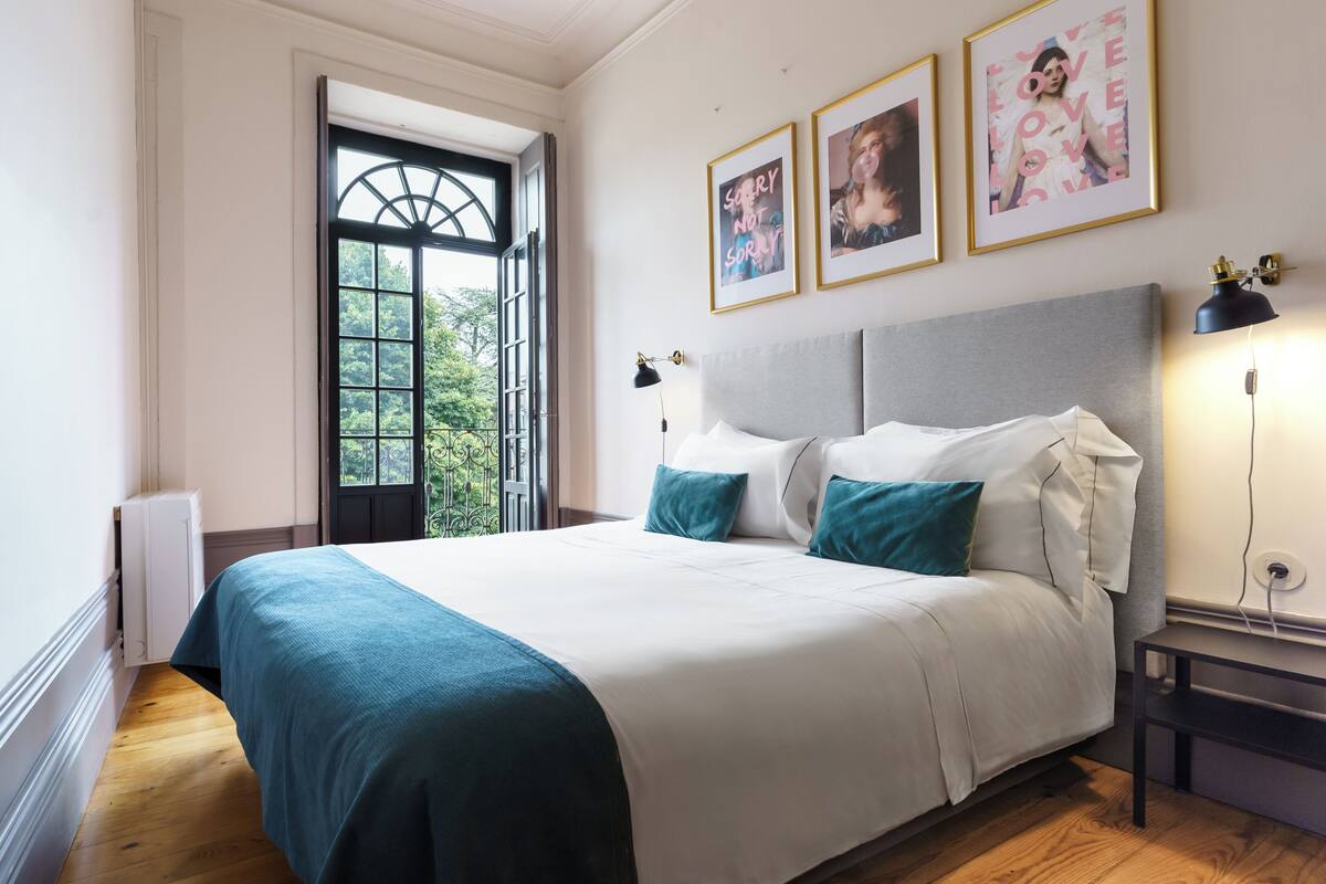 A bedroom with a large bed, a window with a view, and framed pictures on the wall.