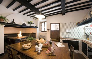 Une cuisine chaleureuse avec une table en bois dressée pour le repas, une cheminée et un crédence décorée.