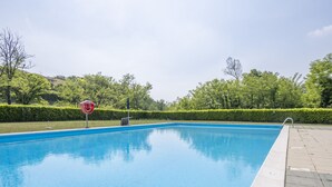 A rectangular swimming pool with a clear blue water surface, surrounded by a low hedge and a paved walkway. - Lisa's Apartment (Muscoline)