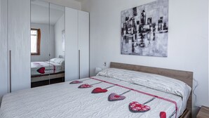 Een slaapkamer met een groot bed, een spiegelkast en een wanddecoratie met abstracte kunst.