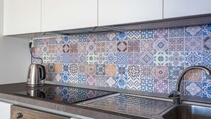 Een keuken met een betegelde achterwand, roestvrijstalen apparatuur en een spoelbak.