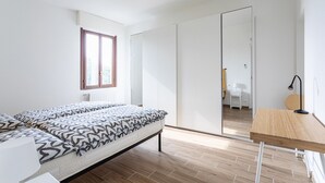 Quarto moderno com cama, escrivaninha de madeira e guarda-roupa.
